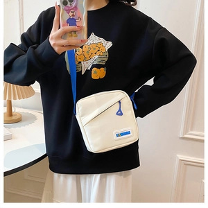 Vue détaillée du sac bandoulière en toile crème avec sangle bleue et logo Fashion