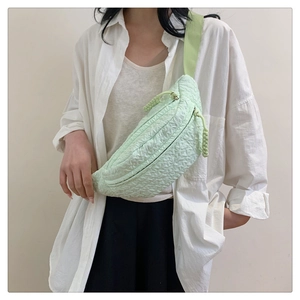 Close-up of light green bubble textured fabric and woven zip pullers on chest bag