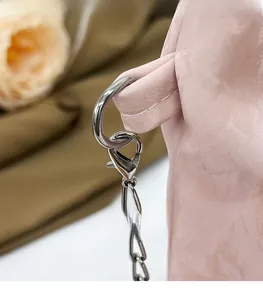 Detailed close-up of light pink beaded handbag with durable silver metal chain and lobster clasp