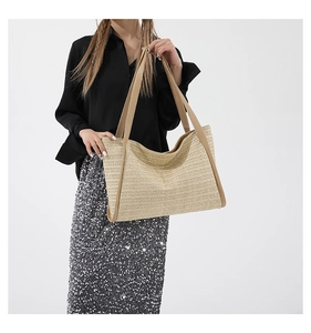 Close-up of woven paper straw tote bag with brown leather straps for summer beach