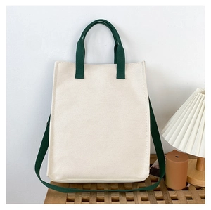 Detail of a minimalist canvas tote bag with cream body and green adjustable straps