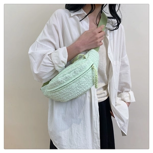 Detail shot of light green bubble textured crossbody bag worn by a model in soft light