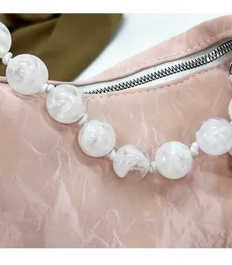 Detail of pink marble textured handbag with creative white marble beaded handle and silver zipper