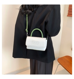 Mini sac à bandoulière en cuir blanc avec poignée tissée verte sur blazer noir chic
