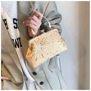 Detail view of champagne sunburst sequin clutch bag with golden ring handle and chain