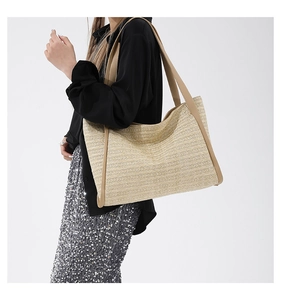 Side view of woven straw tote bag with brown leather handles on fashion model