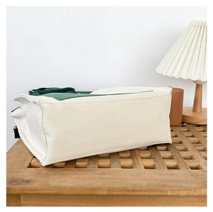 Close-up of thickened canvas tote bag base with green stitching and wide bottom