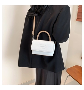 Détail d'un sac bandoulière blanc en cuir avec poignées tressées et logo gravé