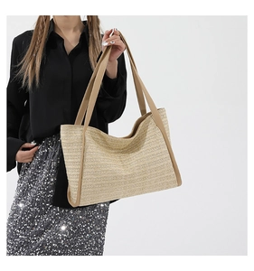 Close-up of woven straw tote bag with brown faux leather handles and fine texture