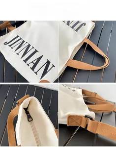 Vue détaillée du sac cabas en toile crème avec lettrage JINNIAN et fermeture éclair