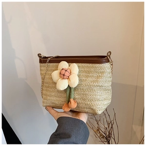 Détail du sac seau en paille tressée avec fleur et bandoulière chaîne dorée