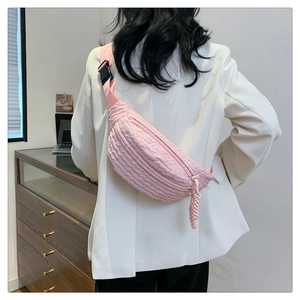 Detail view of pink pleated texture waist bag with adjustable strap worn as crossbody