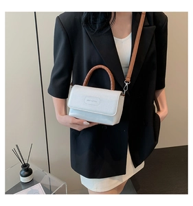 Détail d'un sac blanc à motif litchi avec poignée tressée marron et logo de la marque