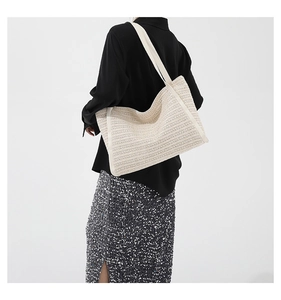Minimalist beige woven tote bag shown as a spacious shoulder bag on a fashion model