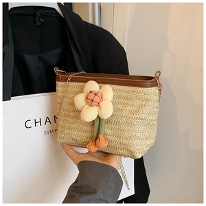 Détail du sac seau en paille tressée à la main avec breloque fleur et chaîne en métal