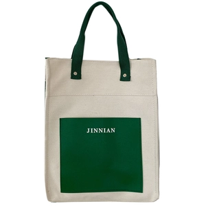 Detail of canvas tote bag showing green pocket with JINNIAN logo and metal rivet hardware