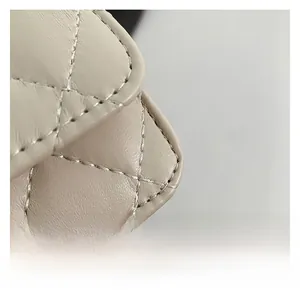 Dettaglio ravvicinato della pelle trapuntata beige e cuciture fini della mini borsa a tracolla