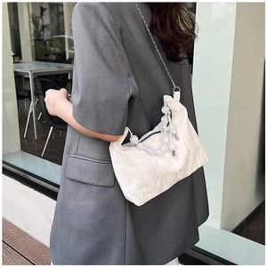 Close-up of white pleated crossbody bag with elegant bead chain and metal strap details