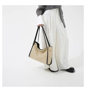 Detail view of woven straw tote bag with black leather handles for summer beach vacations