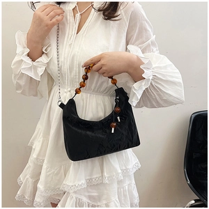 Detail of black pleated cloud bag with amber beaded handle and silver chain strap