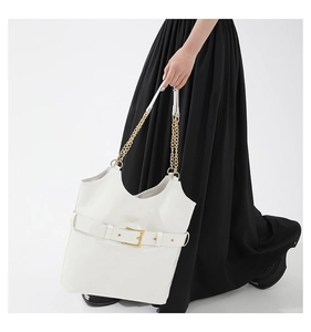 Détail d'un sac cabas en cuir blanc avec boucle décorative et bandoulière dorée