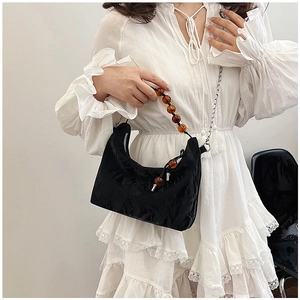 Detail of black pleated cloud bag with amber bead handle and silver chain strap