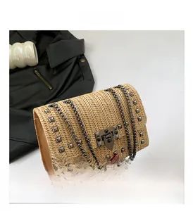 Détail du tissage en paille et des clous métalliques noirs sur le sac à bandoulière