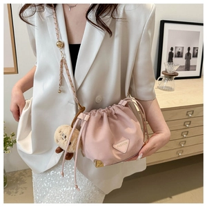 Pink drawstring bucket bag with gold chain strap and teddy bear charm on model