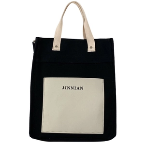 Close-up of black and white color-blocking canvas tote bag with JINNIAN printed pocket