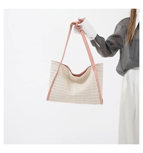 Detail view of woven tote bag with contrast pink leather straps held by a model