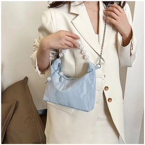 Detail of light blue pleated handbag with acrylic beaded handle and metal chain strap
