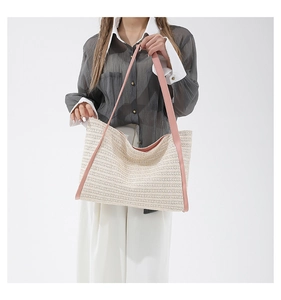 Close-up of woven straw tote bag texture with elegant pink handles for summer