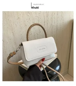 Détail d'un sac blanc en cuir avec poignée tissée kaki et logo de la marque