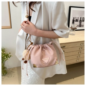 Detail of light pink bucket bag featuring drawstring closure and gold metal corner guards