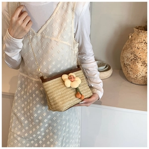 Détail du sac seau en paille tressé à la main avec breloque fleurie et chaîne