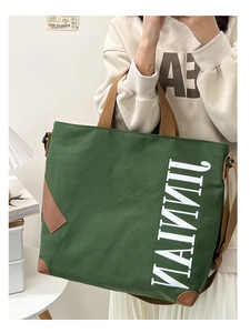 Détail d'un sac cabas en toile vert foncé avec anses marron et design de texte blanc