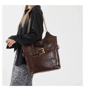 Détail du grand sac cabas en cuir ciré marron avec boucle et bandoulière sur le mannequin