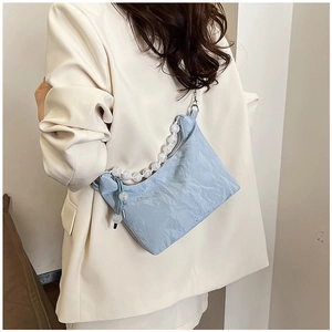 Detail of light blue cloud bag with pleated texture and white bead strap on model