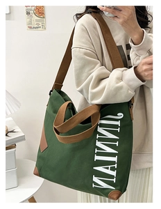 Détail du sac fourre-tout en toile verte avec bretelles brunes et lettrage blanc