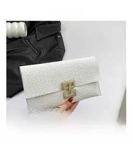 Detail of white envelope clutch bag with crocodile texture and gold metal buckle