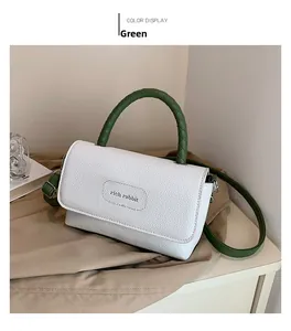 Détail de la poignée tissée verte et du logo rich rabbit sur le sac carré blanc texturé