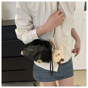 Close-up of black pleated bucket bag with gold triangle logo and chain strap