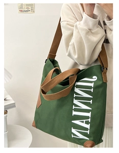 Détail du grand sac cabas en toile vert foncé avec anses brunes et logo blanc imprimé