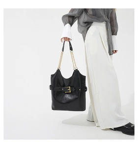 Détail du sac hobo en cuir brillant noir avec boucle dorée et bandoulière en chaîne