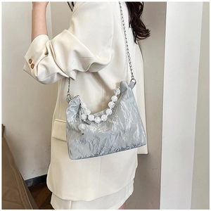 Detail of silver pleated crescent bag with oversized marbled beads and chain strap