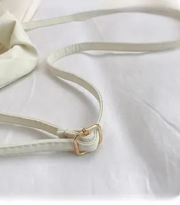 Detail of white leather shoulder strap with adjustable golden metal buckle and stitching