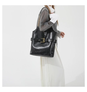 Vue détaillée du grand sac cabas noir brillant avec boucle dorée et bandoulière chaîne
