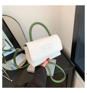 Détail de la texture cuir blanc et de la poignée tressée verte du petit sac carré