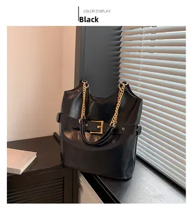Détail du cabas en cuir noir brillant avec poignée chaîne dorée et boucle de ceinture