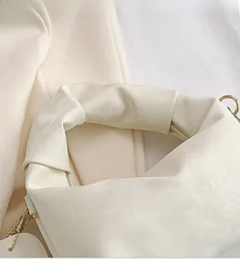Detail of soft cream suede handbag featuring a thick comfortable handle and gold hardware